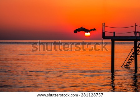 Young boy jumping in water from pier