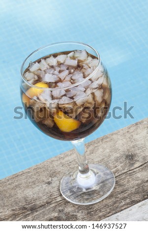 Glass of cola with ice at the swimming pool