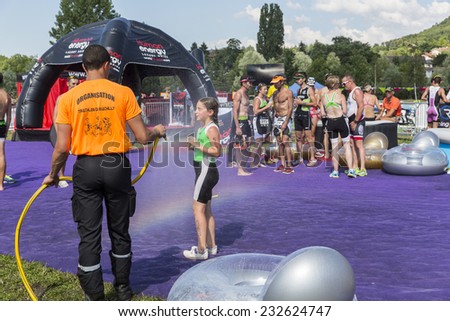 MACHILLY, FRANCE -JULY 6, 2014: Unidentified athlete cools off with a rainbow shower after the Lake Machilly Triathlon which is part of the TriSaleve of Annemasse organization.