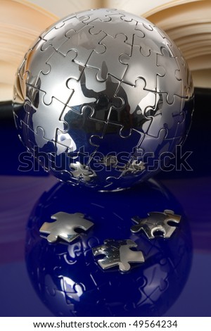 Globe puzzle with book on blue background.