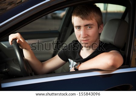 Young man sitting on the driver seat in luxury car