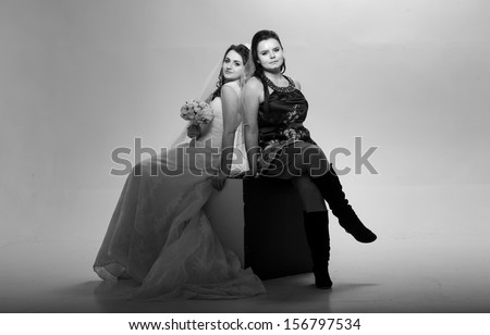 Black and white photo of young bride posing with her friend in studio