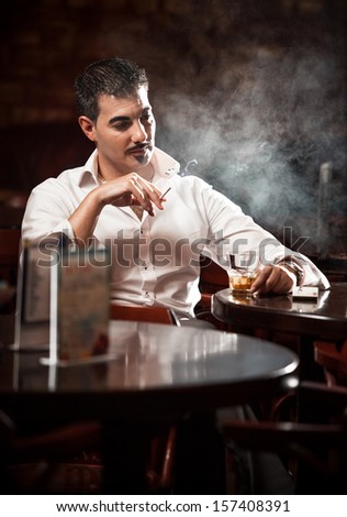 Sexy man in shirt sitting at the table and smoking