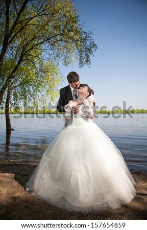 Handsome groom hugging from back bride on white dress