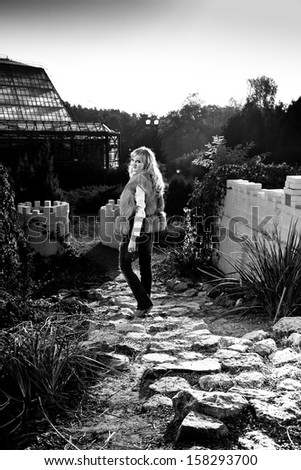 Black and white photo of elegant woman going on paving road in mountain village