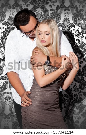 Handsome man hugging blond girl from back and holding hands on her booty