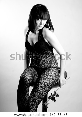 Black and white photo of brunette woman posing in provocative sheer clothes