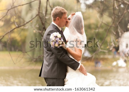 Closeup portrait of newly married couple hugging at park near lake