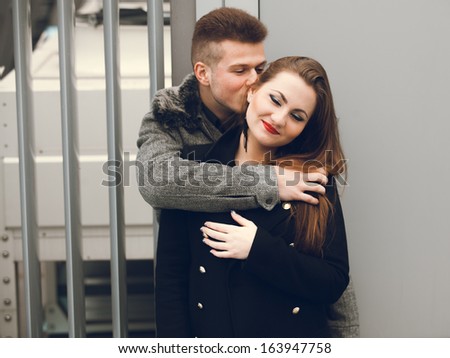 Handsome young man kissing in ear his girlfriend on street