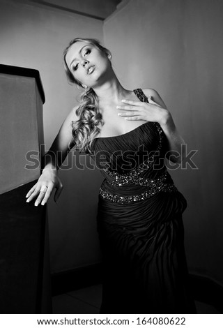 Black and white portrait of sexy curly woman in black evening dress