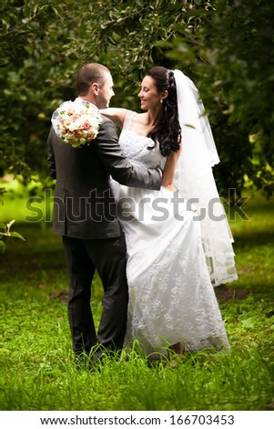 Wedding couple hugging and looking at each other at garden under trees