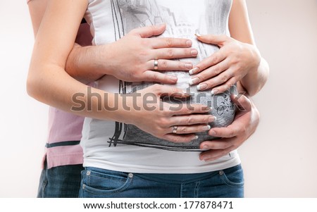 Closeup photo of men hands hugging women pregnant abdomen