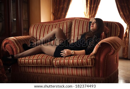 Sexy beautiful woman lying on couch at luxurious interior