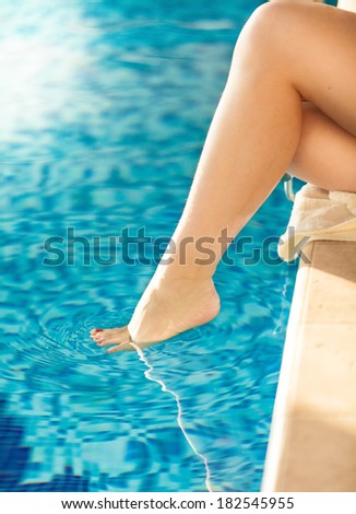Closeup shot of woman dangling sexy leg in swimming pool