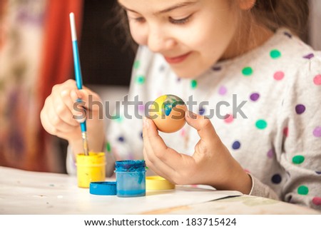 Happy little girl painting easter egg