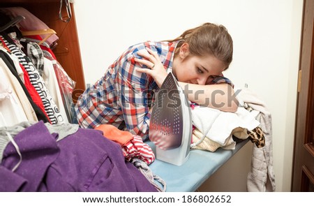 Photo of exhausted woman ironing big pile of clothes
