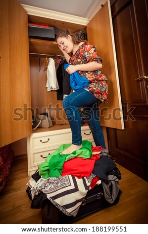 Beautiful woman packing suitcase on holiday at wardrobe