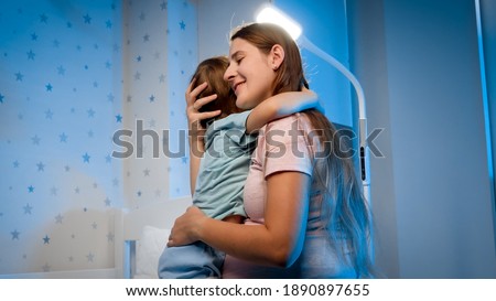 Beautiful young mother talking to her little toddler boy being scared of nightmare at night. Parent soothing and caressing child. Foto stock © 