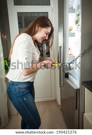 Adult woman trying to cut chain on fridge with pliers