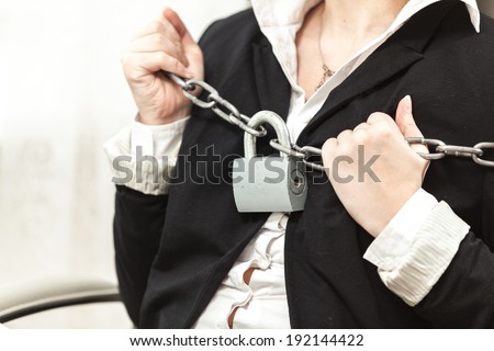 Closeup photo of businesswoman being locked by chain and padlock