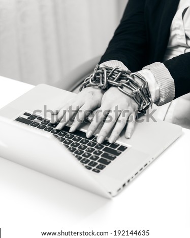 Black and white closeup photo of woman locked to laptop by chain