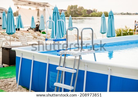 Outdoor shot of inflatable swimming pool with metal frame on beach
