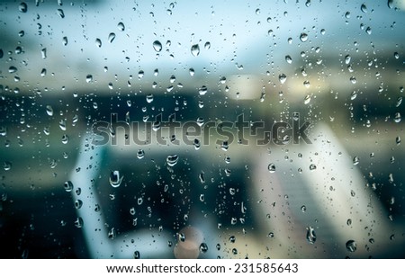 View on wet street at rainy day through window with water drops