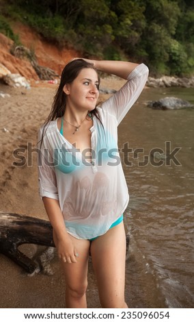 Beautiful brunette girl in wet shirt on sea beach