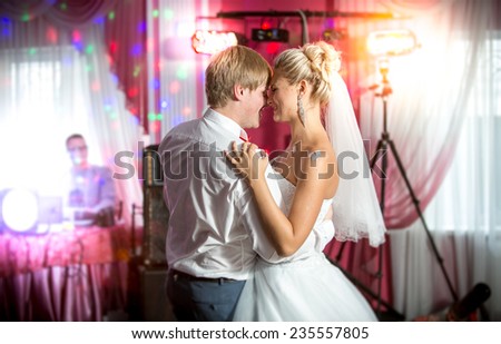 Beautiful newly married couple dancing at colorful lights and flares
