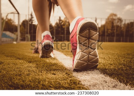 Toned photo of slim woman running on grass field