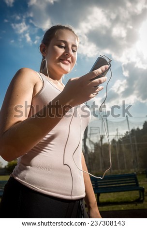 Portrait of smiling sporty woman using mobile phone while running