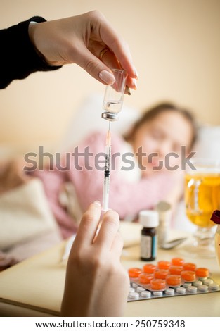 Closeup photo of young woman filling syringe from ampule next to child bed