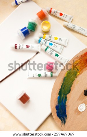 Closeup photo of chaos of tools and paint tubes on white canvas