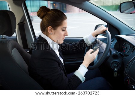 Portrait of young businesswoman driving a car and using phone