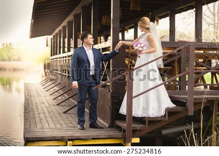 Beautiful bride and handsome groom walking down the stairs on pier