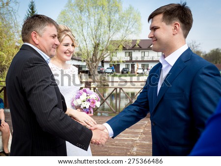 Portrait of brides father shaking hands with groom at wedding ceremony