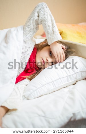 Portrait of sick girl lying in bed and holding hand on head