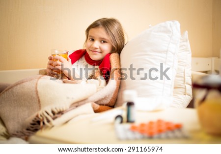 Little girl caught flu and drinking hot tea with lemon in bed