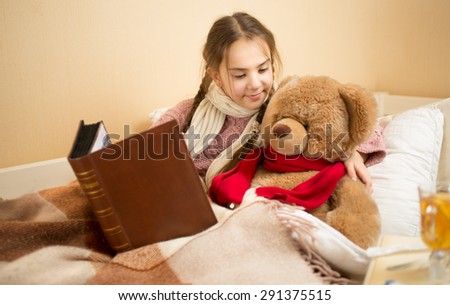 Portrait of cute girl telling story to teddy bear at bed