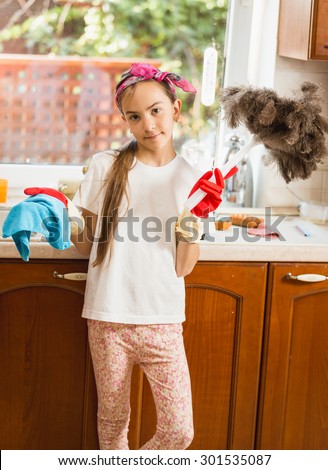 Portrait of cute girl cleaning mess on kitchen with cloth and brush