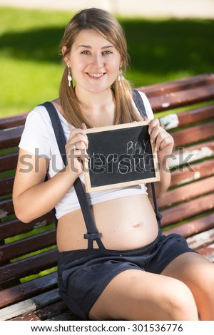 Portrait of smiling pregnant woman sitting on bench and guessing of baby\'s sex