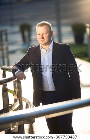 Closeup portrait of stylish young businessman posing on street at sunny day