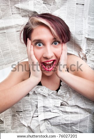 Young caucasian lady shouting and screaming through big hole in magazine page