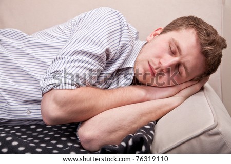 Young attractive man is sleeping on couch