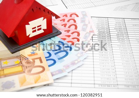 Toy house and money on the documents.