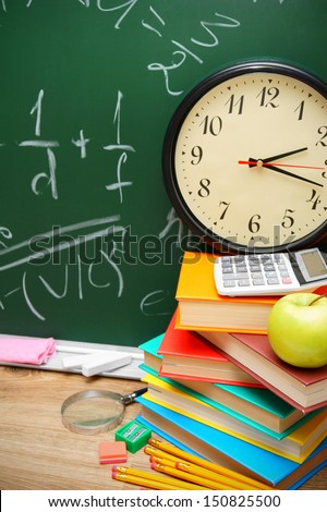 Back to school. Watch and school accessories against a school board (mathematical formulas)