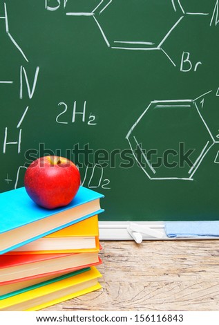 Apple on books. Against a school board with chemical formulas.
