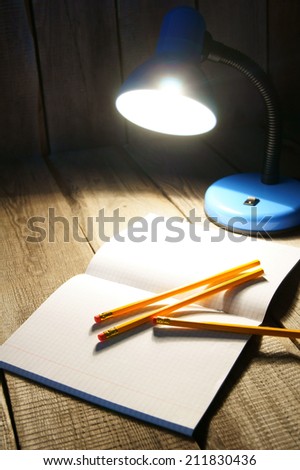 Open writing-book and the fixture. On a wooden background.