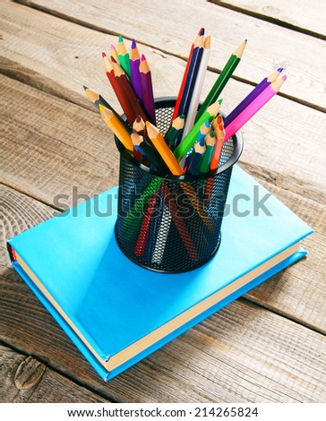 Pencils and book . On a wooden background.