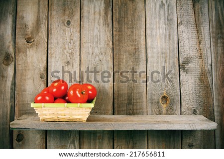 Tomatoes in a basket on a wooden shelf. On a wooden background.